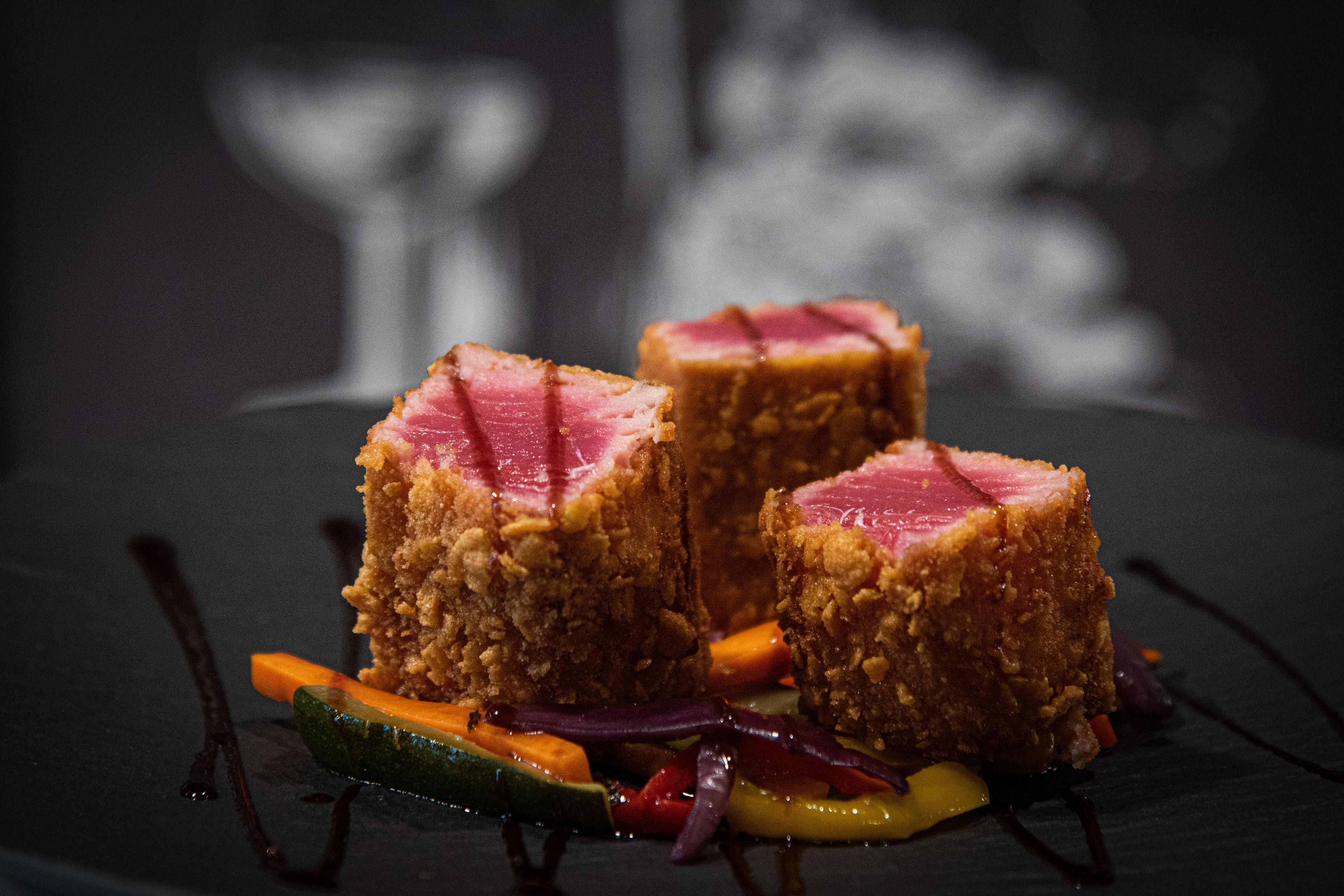 Thon mi-cuit en croûte croustillante, dressé dans la lumière tamisée du restaurant
